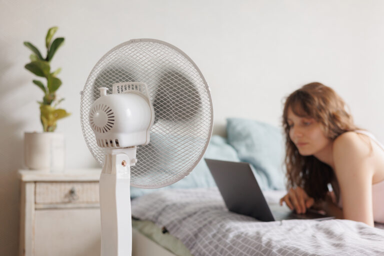 Vrouw koelt slaapkamer met ventilator
